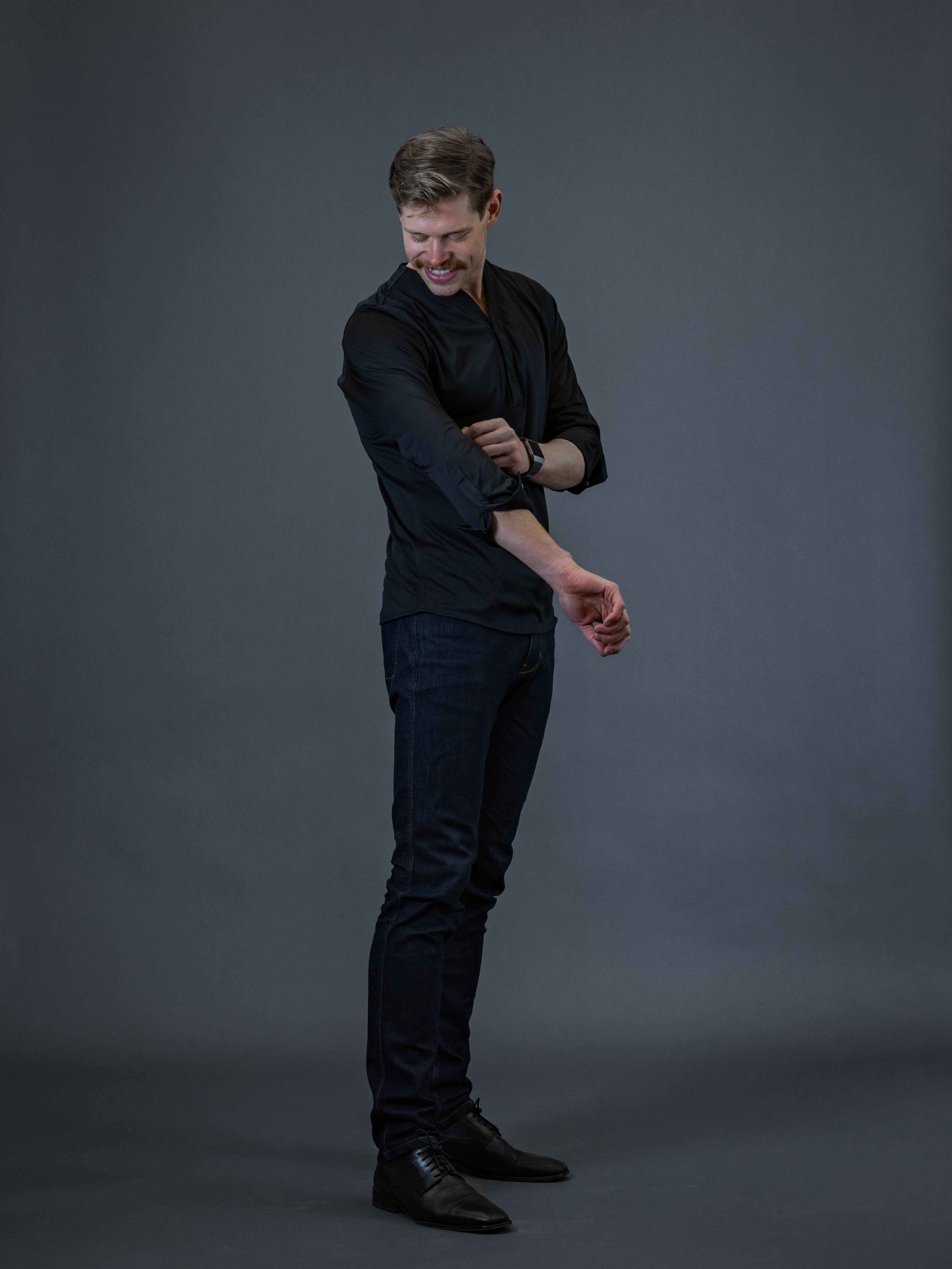 Young man wearing a black mandarin collar shirt with dark jeans