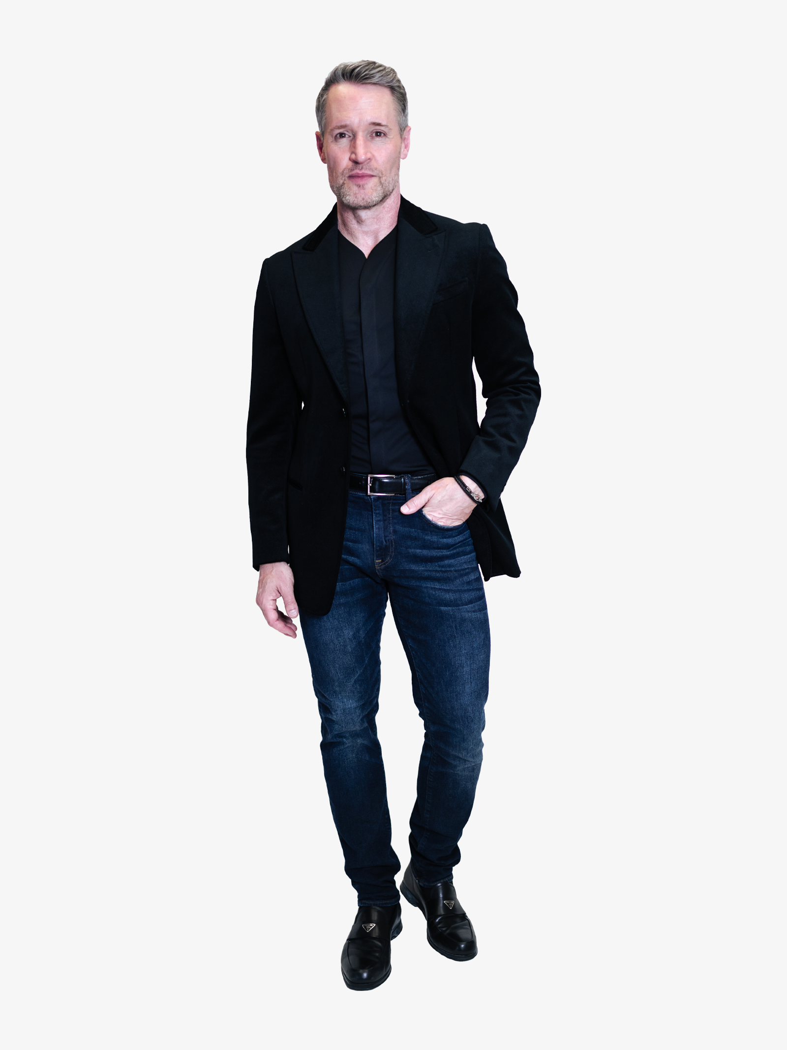 Man wearing a mens collarless dress shirt in black tucked in, with a nice pair of jeans and a dark sports coat.