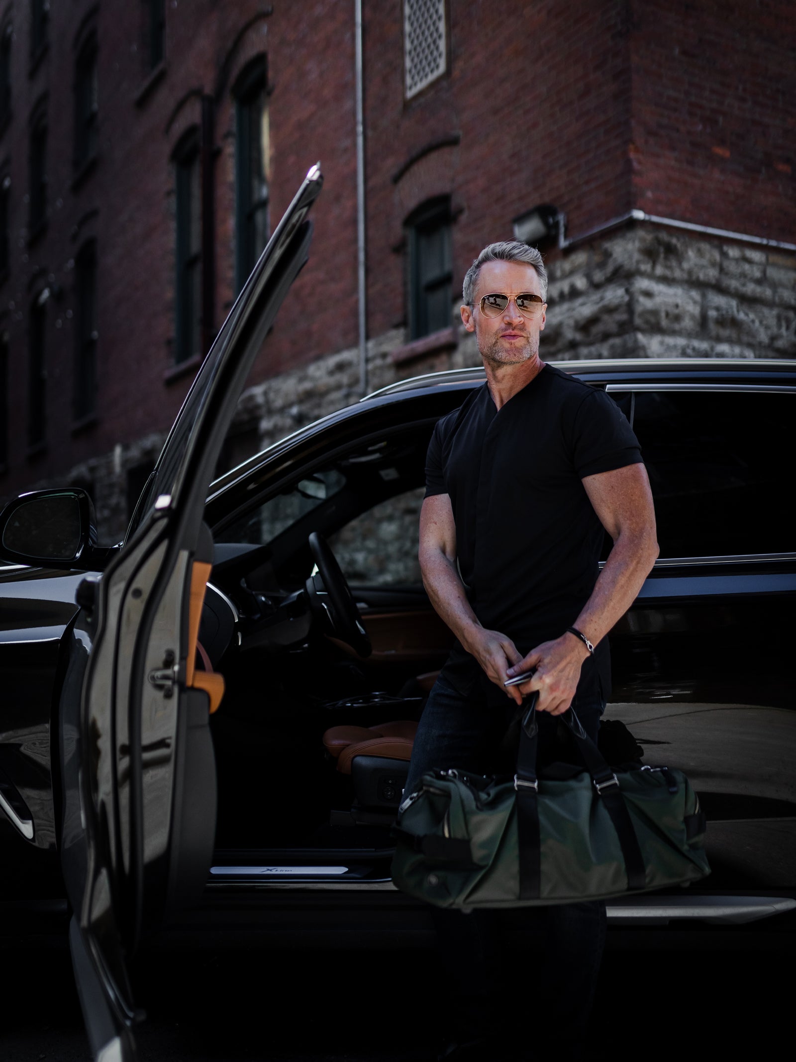 man with black car sunglasses and a black collarless short sleeve shirt