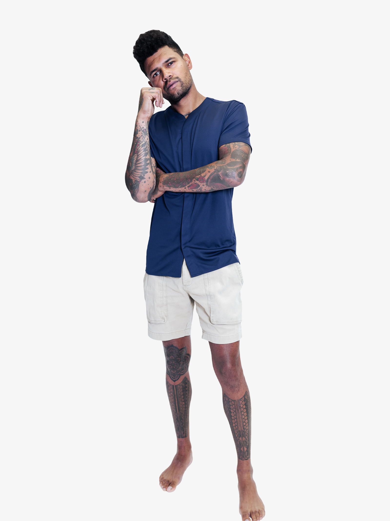 Man with tattoes wearing navy blue collarless short sleeve shirt with light deep pocket shorts