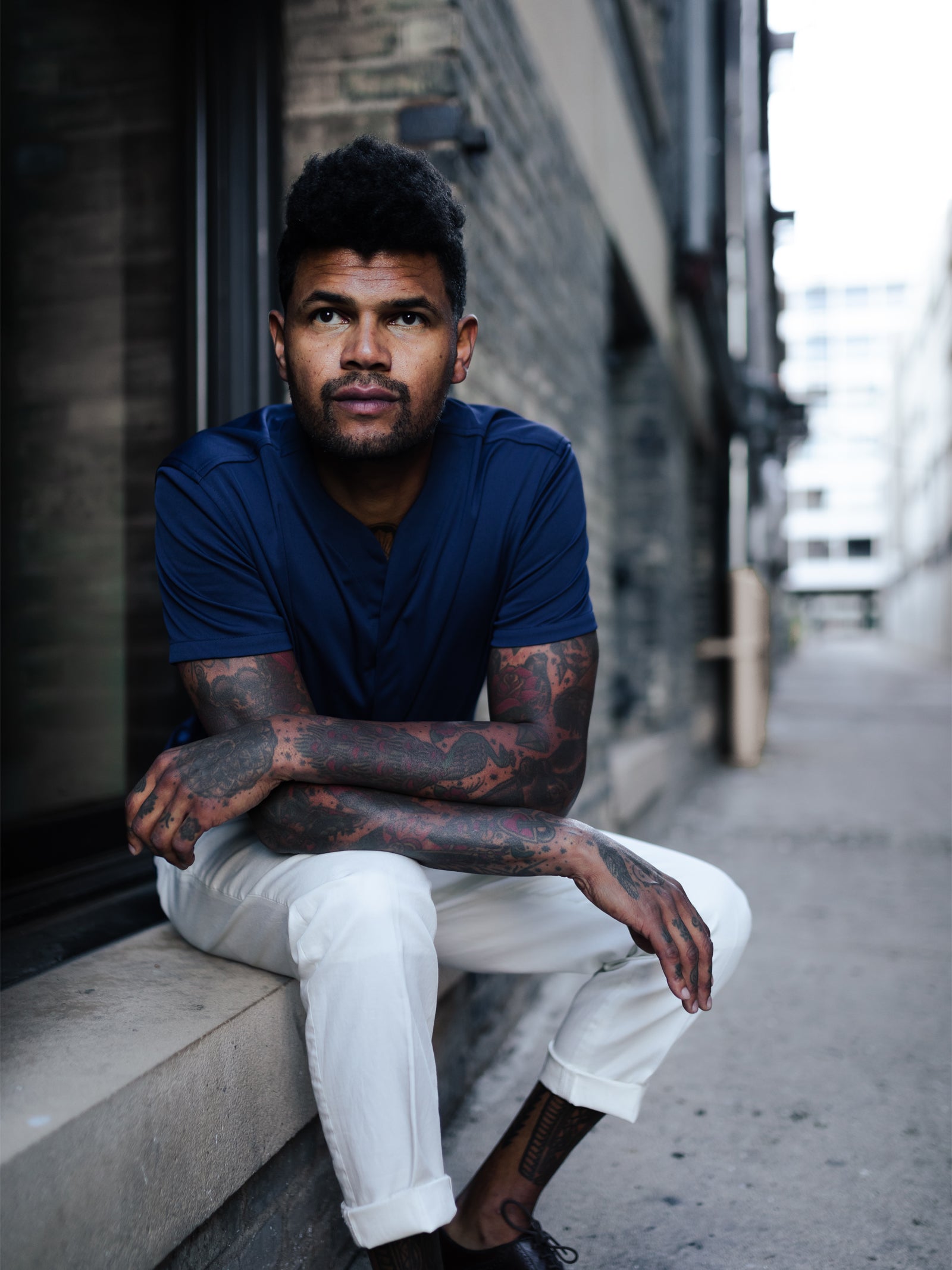 Lifestyle shot of man sitting down with his blue collarless polo and white yacht pants