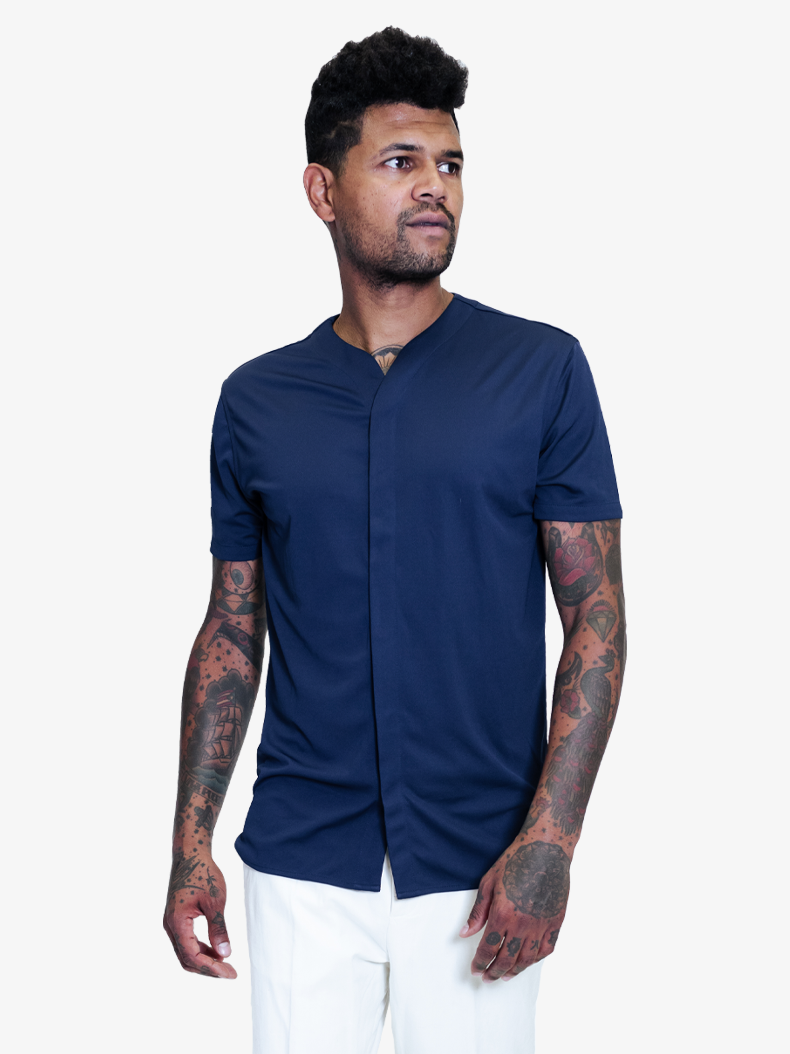 Man with tattoos wearing a dark blue collarless short sleeve shirt styled with white pants