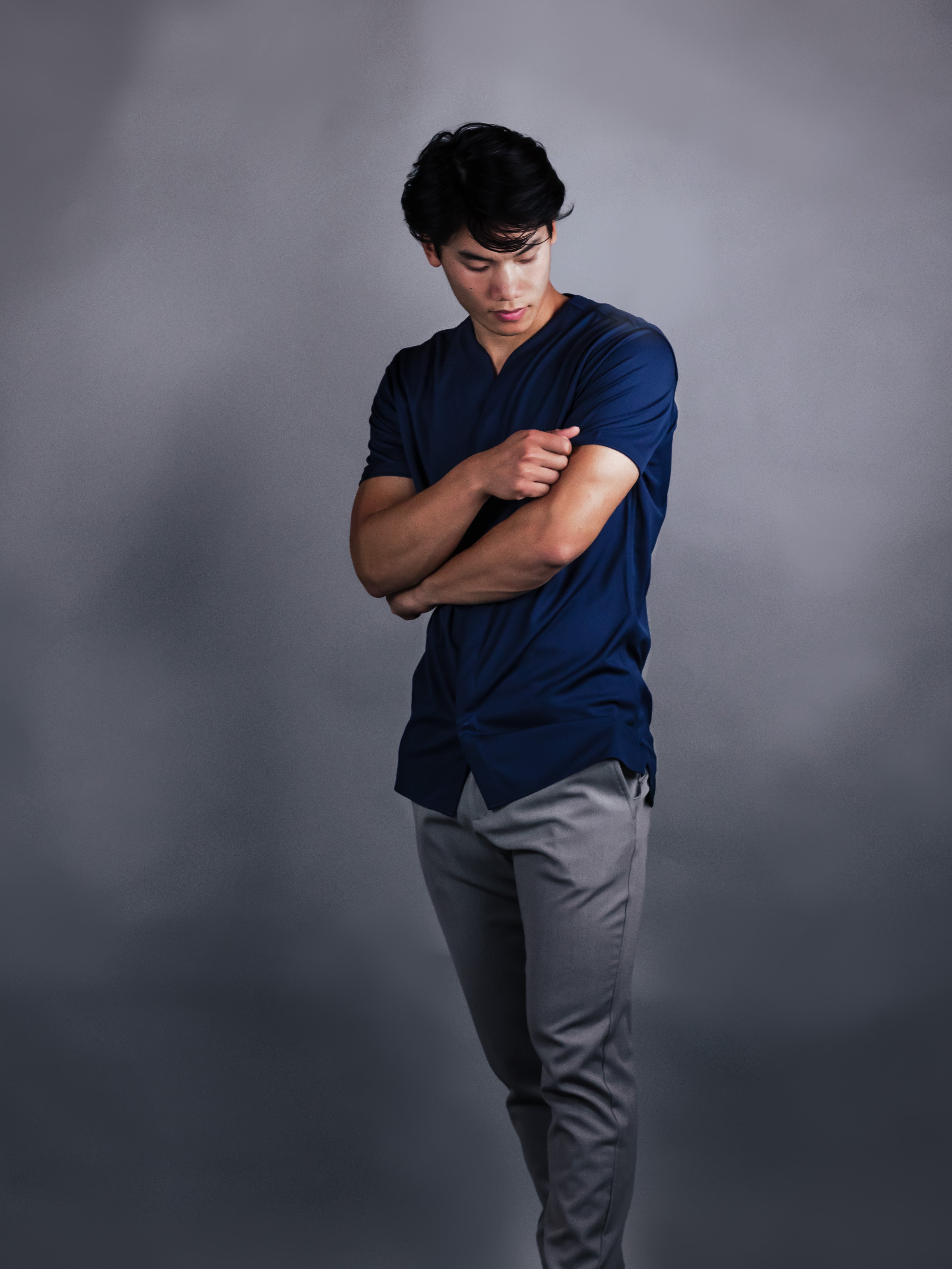 Man looking at the sleeves of a collarless short sleeve dress shirt