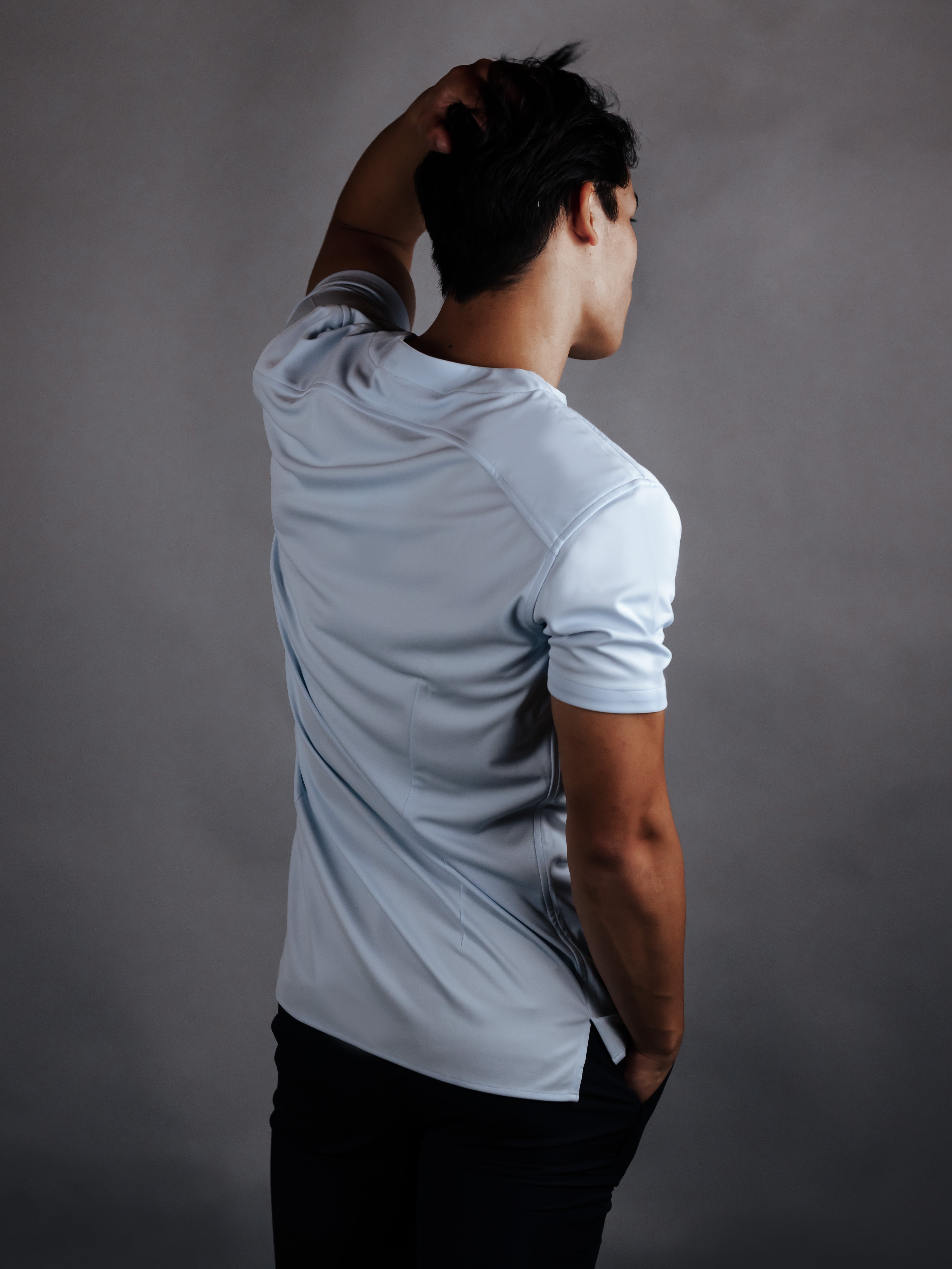 Model showing the back of a cheegs collarless golf shirt in light blue