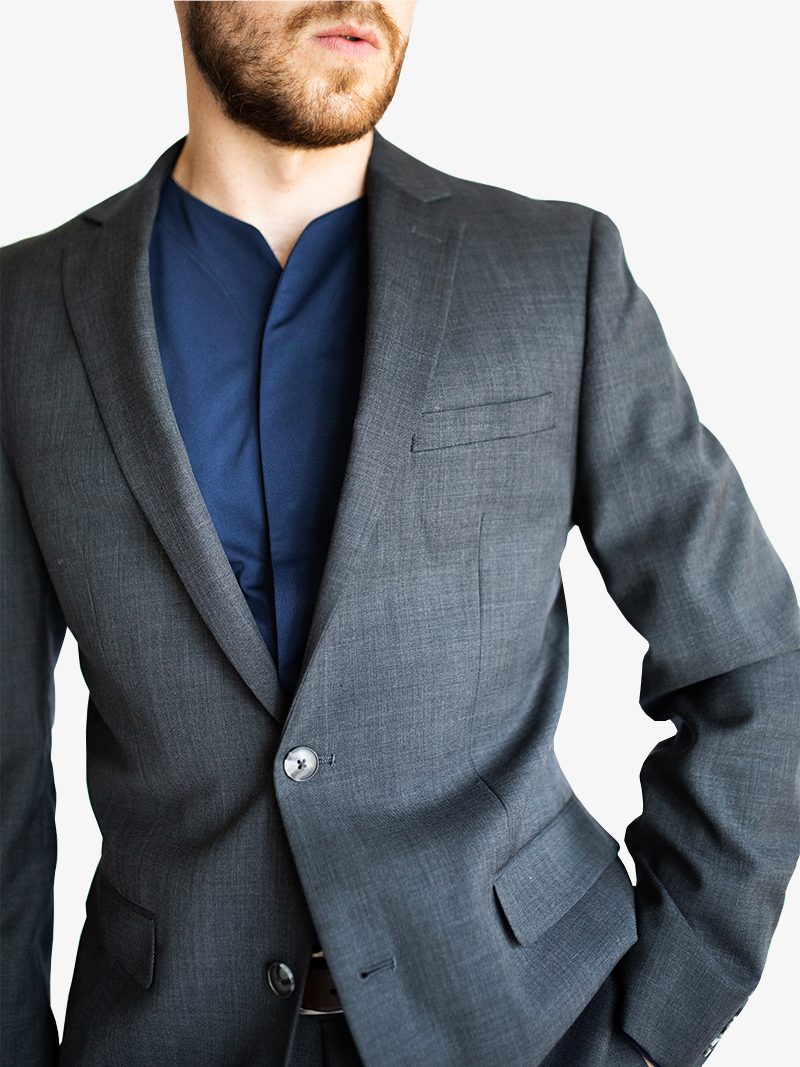 man wearing a gray suit with a formal collarless shirt under it in dark blue. 