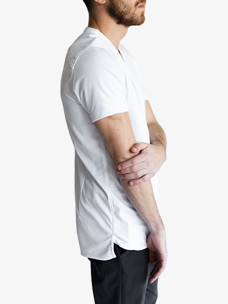 Man turned to the side wearing a white collarless short sleeve shirt and dark pants